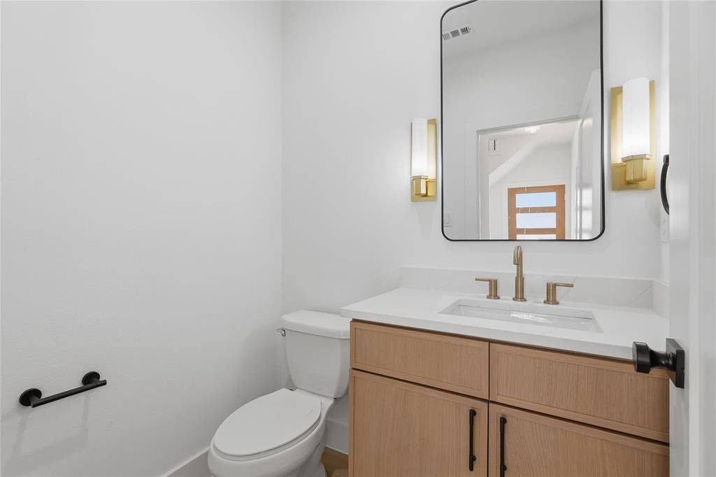 3300 S Harwood Street, Dallas, TX 75215 Wood-finish vanity with white countertop, undermount sink, and brass-finish faucet