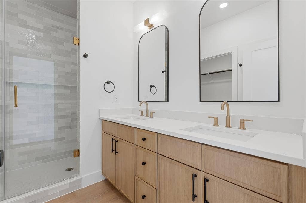 3300 S Harwood Street, Dallas, TX 75215 Dual vanity with white countertops, light wood-finish cabinetry, and gold-finish fixtures