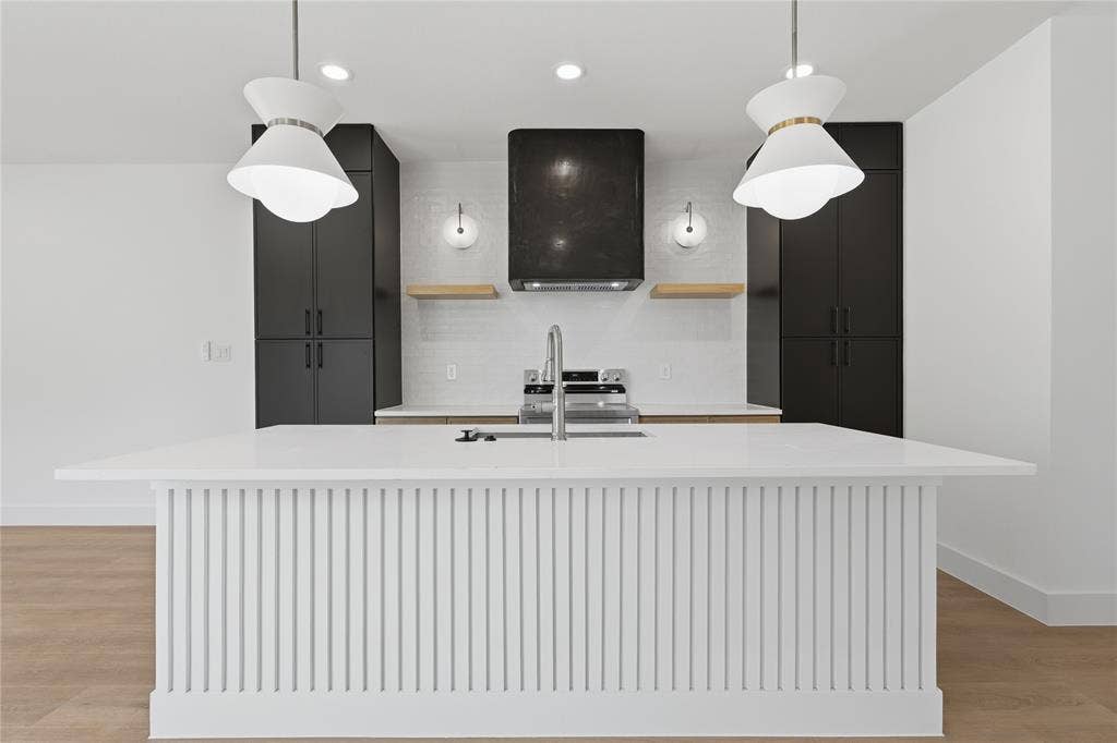 3300 S Harwood Street, Dallas, TX 75215 Kitchen island with vertical slat detailing and a solid surface countertop, equipped with a stainless steel faucet