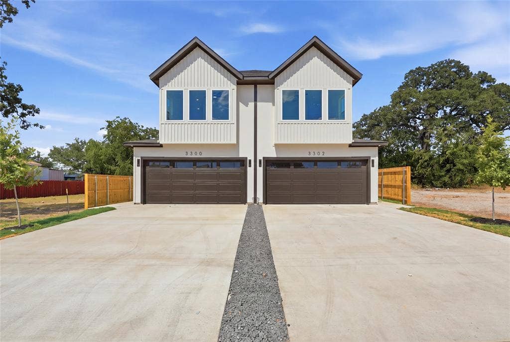 3300 S Harwood Street, Dallas, TX 75215 Modern duplex exterior with white vertical siding, prominent dark brown garage doors, and individual concrete driveways
