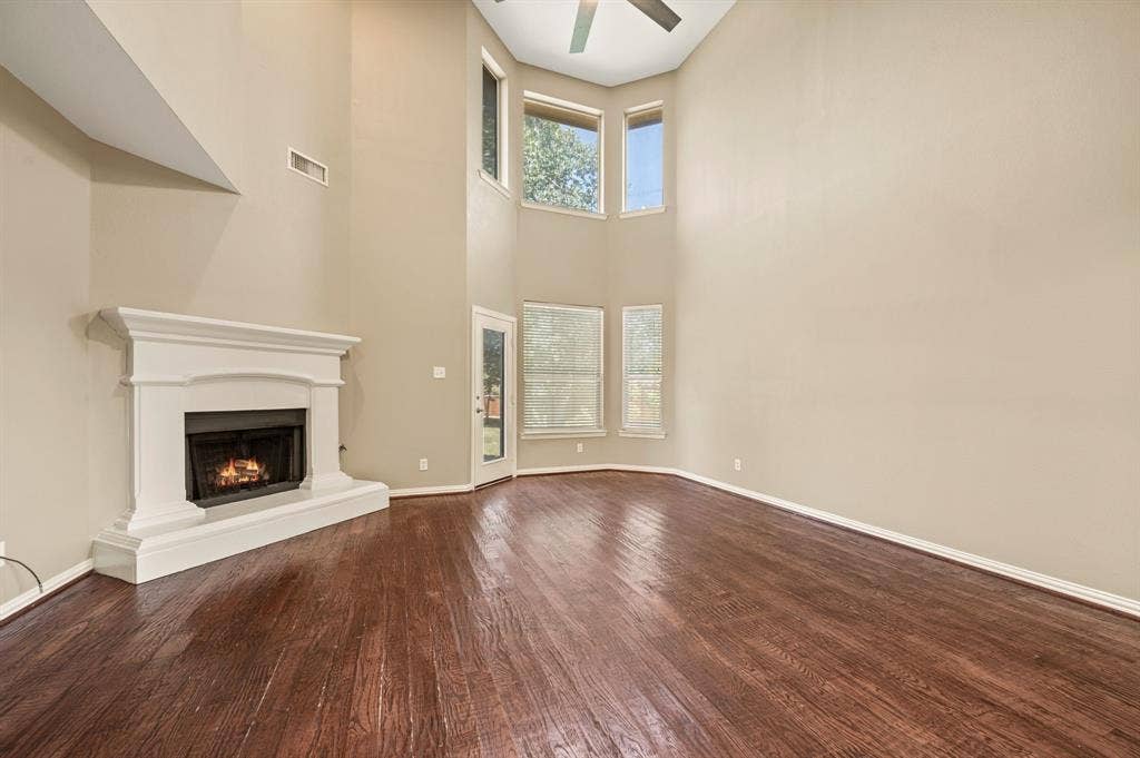 6201 Crator Drive, McKinney, TX 75070 Soaring ceilings, with lovely windows that have window shades to keep the heat out, wood flooring, corner fireplace with fresh painted white mantel, ceiling fan, and wonderful space to host your family and friends