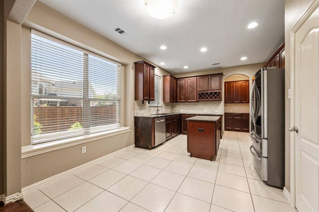 6201 Crator Drive, McKinney, TX 75070 Kitchen featuring wood-finish cabinetry, stainless steel appliances, a center island with granite countertops, and recessed lighting, a wonderful one rack, butlers pantry and wonderful natural lighting!