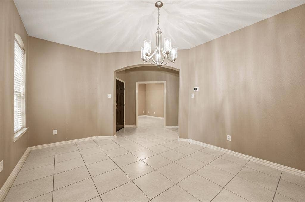 6201 Crator Drive, McKinney, TX 75070 Another view of the dining room with arched entryway a decorative chandelier, tile flooring, and neutral wall tones