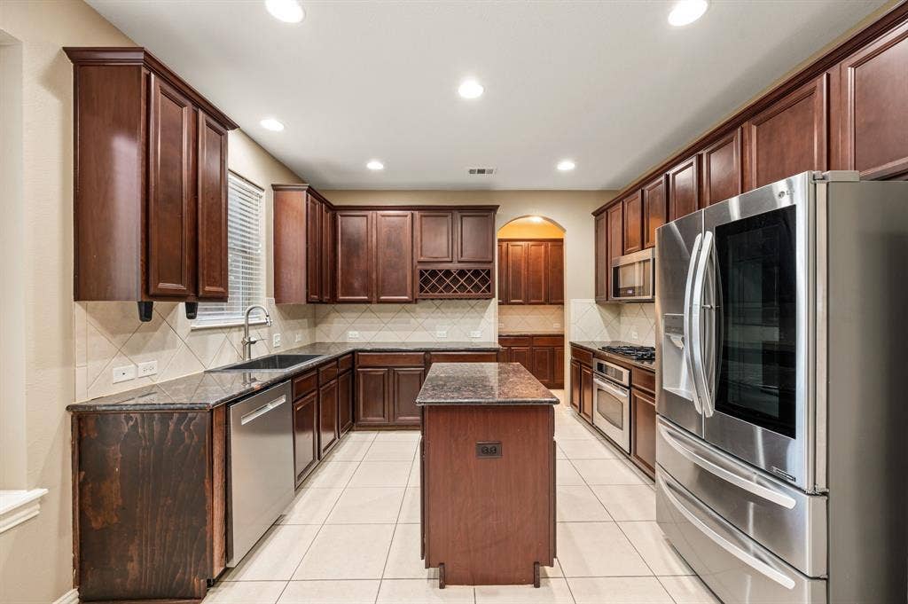 6201 Crator Drive, McKinney, TX 75070 Kitchen featuring dark wood cabinetry, stainless steel appliances, a center island, recessed lighting, with tile flooring ad lots of room to cook with friends and family.