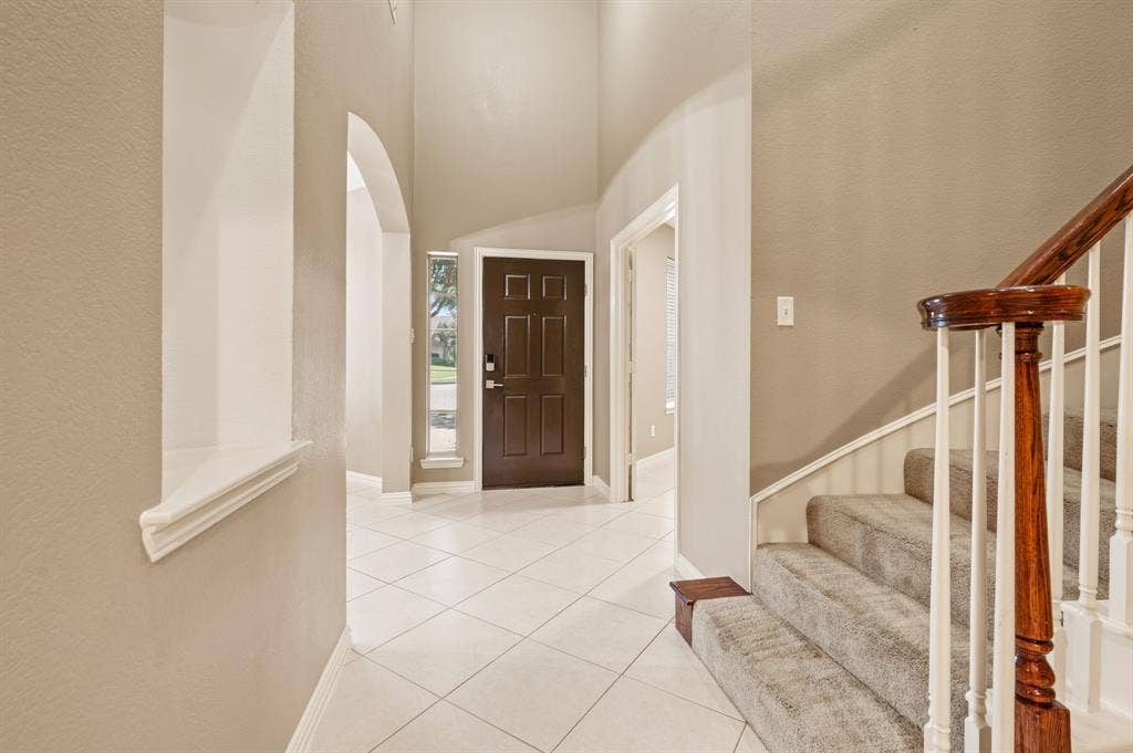 6201 Crator Drive, McKinney, TX 75070 Vaulted, open and bright entryway with tile flooring and an arched doorway ready for you to welcome your friends and family.