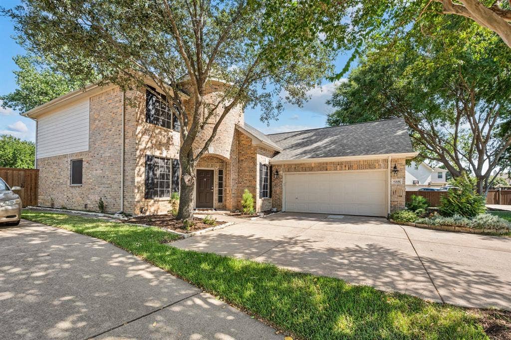 6201 Crator Drive, McKinney, TX 75070 Beautiful home with brick exterior with an arched entryway, two-car garage, and established landscaping