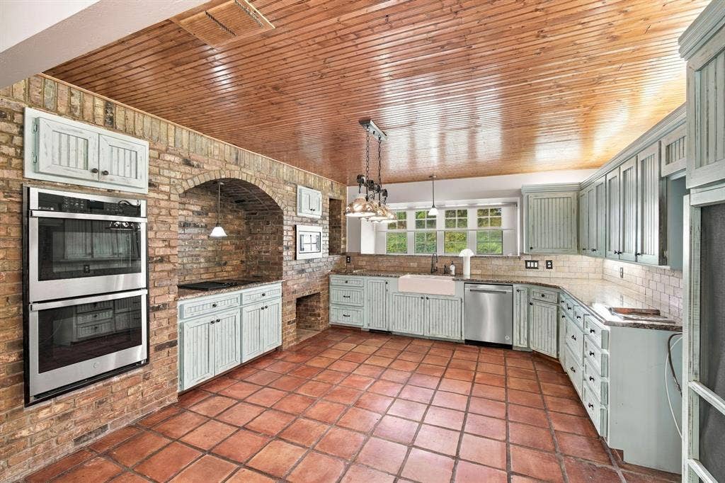 Notice the brick wall housing the double ovens, stove, microwave and cubbies for firewood.