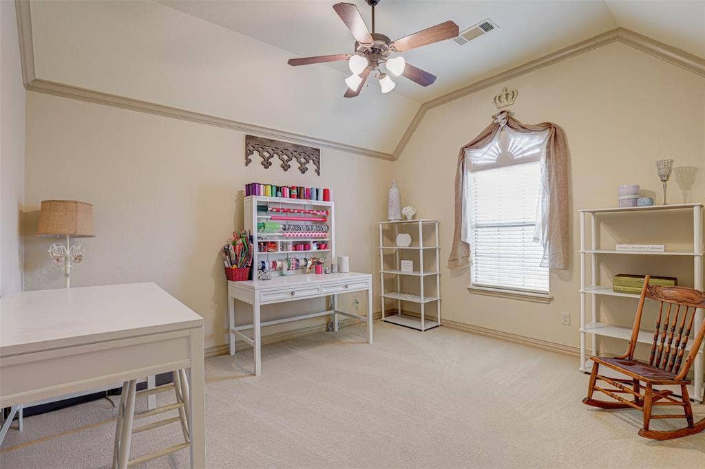Vaulted ceiling with crown molding, ceiling fan with integrated lighting, light-colored carpeting, and window with blinds