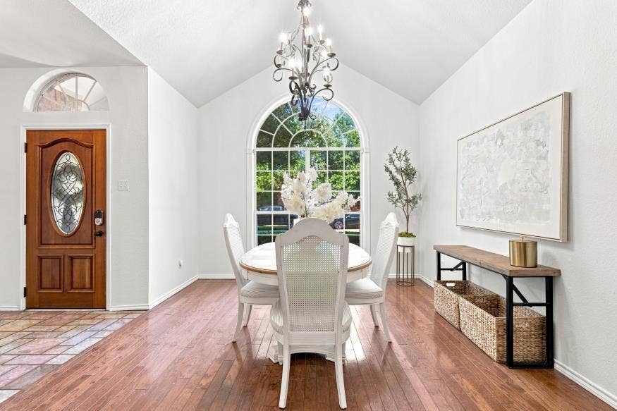 512 Meadowland Drive, Waco, TX 76657 Vaulted ceiling with an ornate chandelier, arched window, wood-finish flooring, and a wood-paneled front door with an oval glass insert