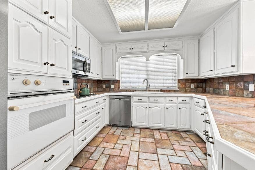 512 Meadowland Drive, Waco, TX 76657 White cabinetry, stainless steel dishwasher, integrated microwave, built-in oven, and a tiled backsplash