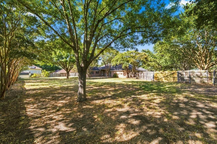 512 Meadowland Drive, Waco, TX 76657 Expansive backyard featuring mature trees, a manicured lawn, and perimeter fencing