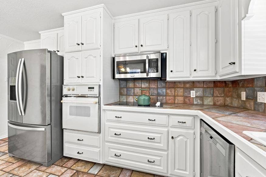 512 Meadowland Drive, Waco, TX 76657 White cabinetry, stainless steel appliances, built-in oven, integrated cooktop, and multi-tone tiled backsplash
