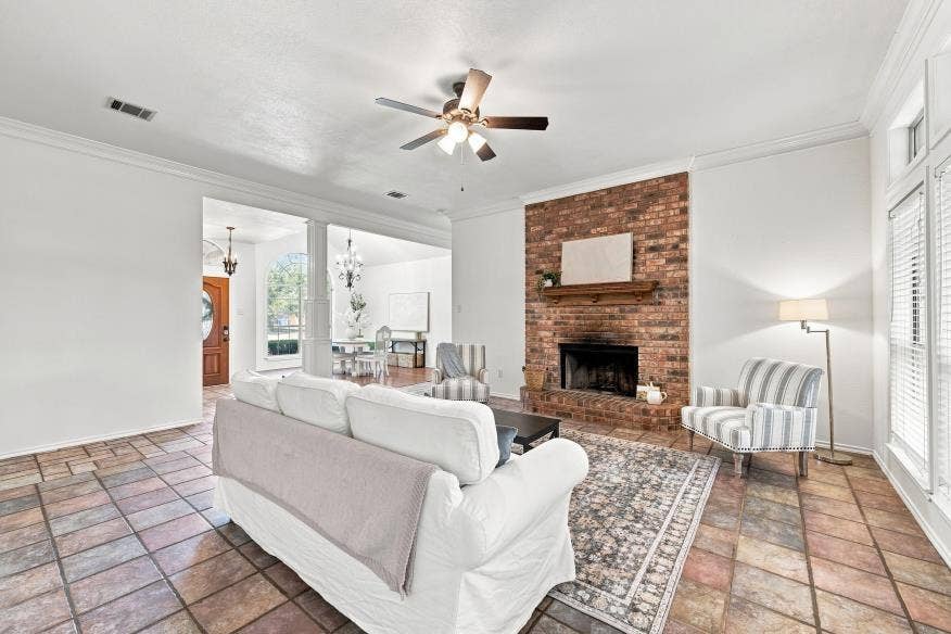 512 Meadowland Drive, Waco, TX 76657 Spacious living area featuring stone tile flooring, a brick fireplace with a wood mantle, and white crown molding