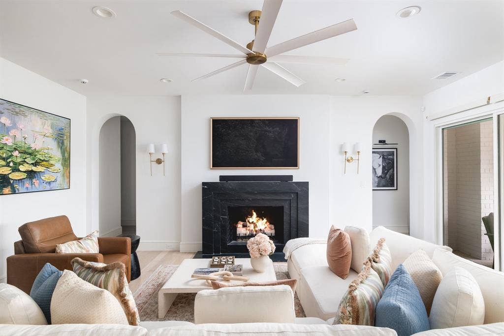 Recessed lighting, arched doorways, a stone fireplace, wood-finish flooring, and sliding glass doors