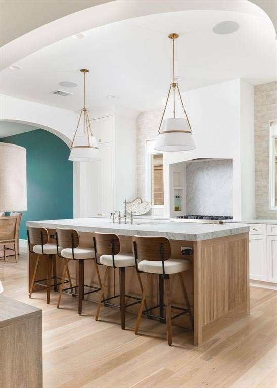 Kitchen island with a light wood-finish base, stone countertop, and integrated sink
