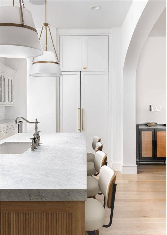 Kitchen island with a light-toned countertop and paneled wood-finish base