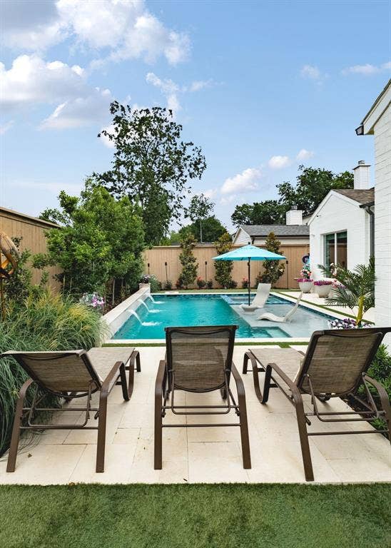 Swimming pool featuring multiple water features, integrated tanning ledge, and light-toned hardscaping