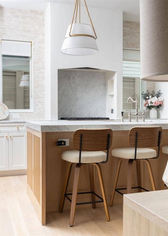 Contemporary kitchen island featuring warm wood cabinetry, a light stone countertop, and seating for two with mid-century modern bar stools