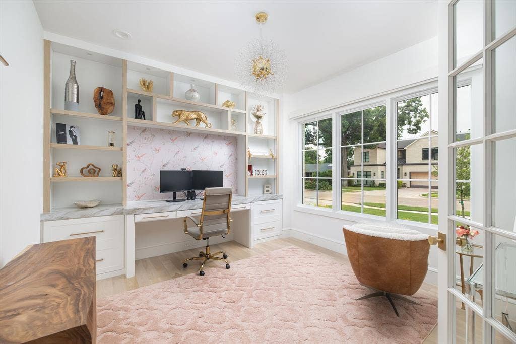 Built-in desk with a marble-finish countertop and integrated shelving, large windows, wood-finish flooring, and French doors