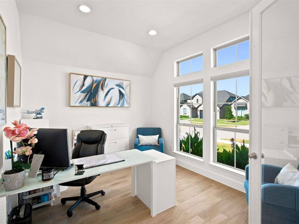 Vaulted ceiling with recessed lighting, multiple large windows, wood-finish flooring, and a white paneled door