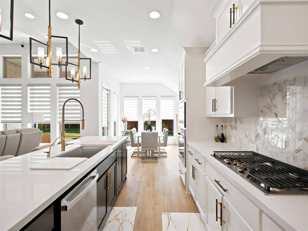 White cabinetry with gold-finish hardware, built-in gas cooktop, patterned tile backsplash, wood-finish flooring, and recessed lighting