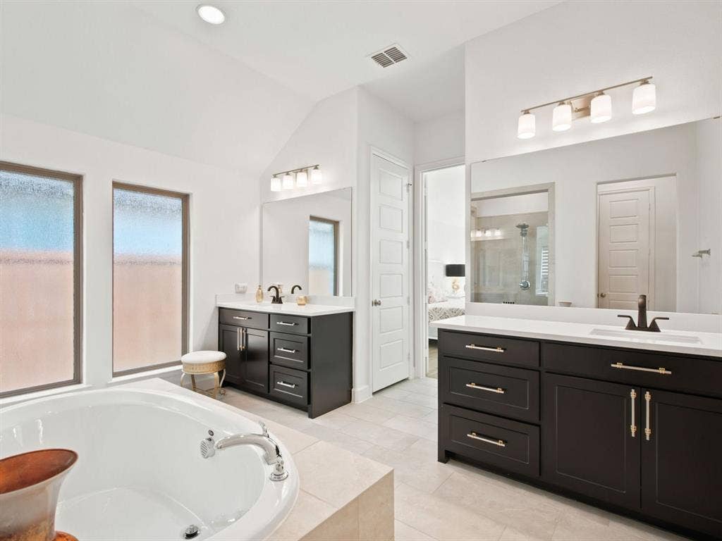 Dual vanities with dark cabinetry and white countertops, recessed lighting, and a built-in tub