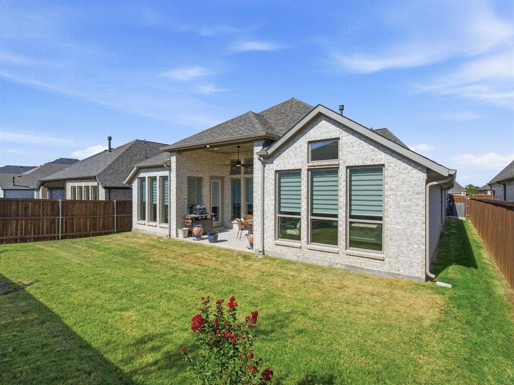 Expansive backyard with a covered patio, manicured lawn, and privacy fencing