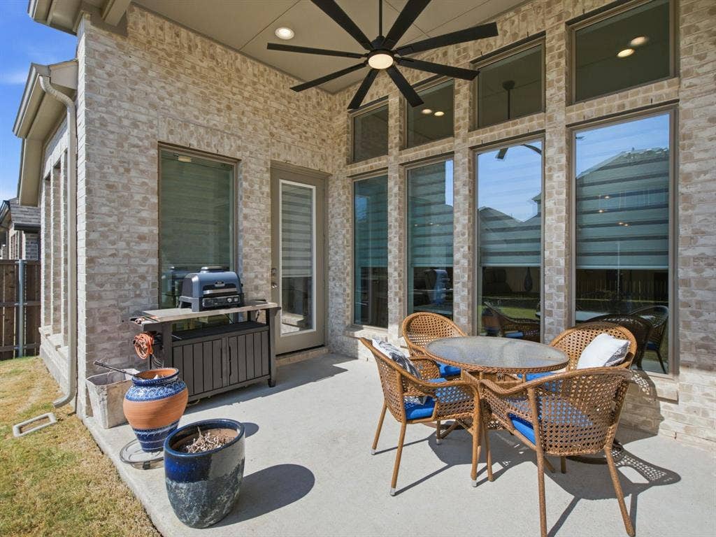 Covered patio with a concrete surface, brick exterior, and a ceiling fan