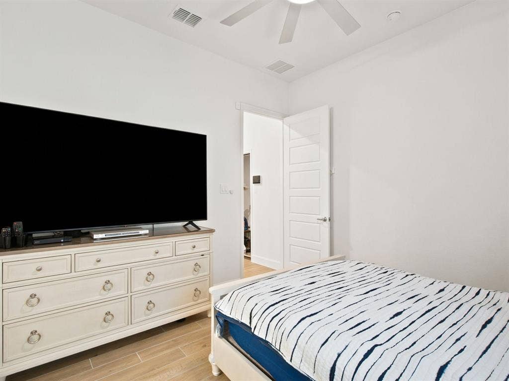 Wood-finish flooring with white walls and a ceiling fan
