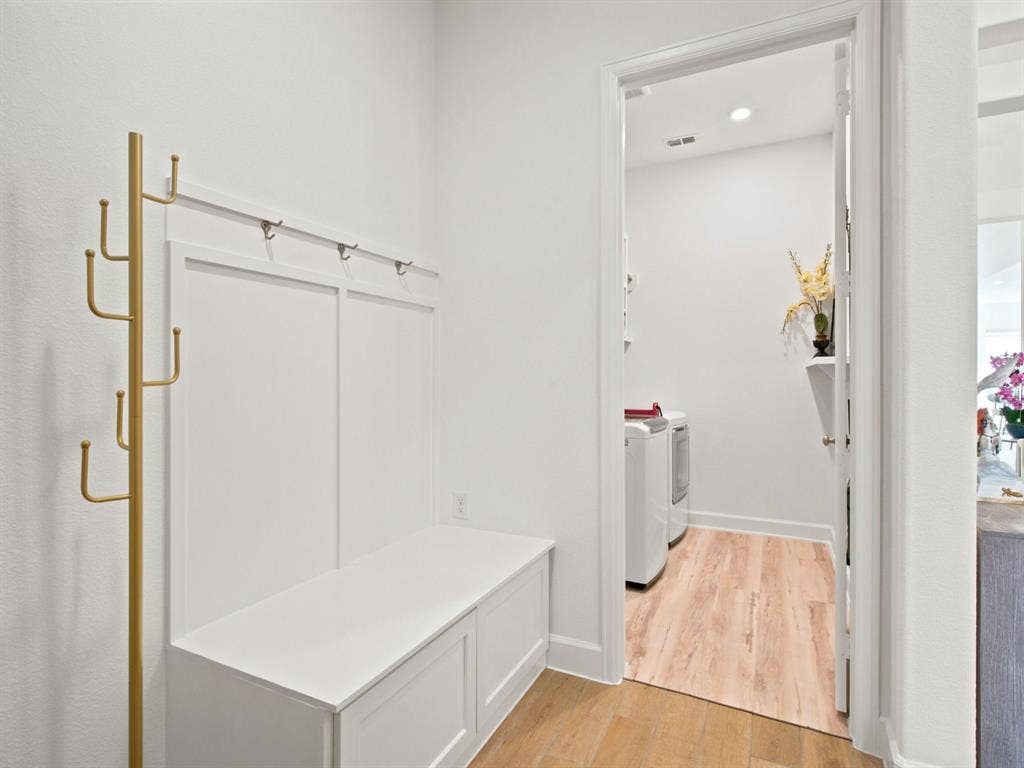 Built-in bench seating with storage, wall paneling with integrated hooks, and wood-finish flooring
