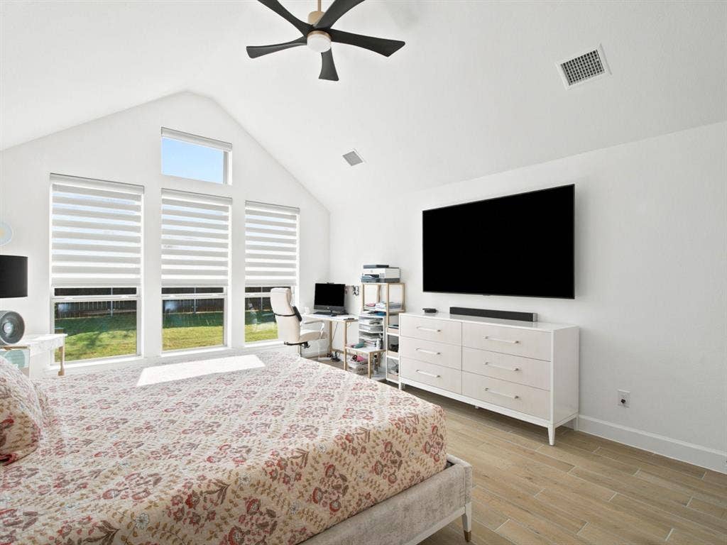 Vaulted ceiling, multiple large windows, wood-finish flooring, ceiling fan, built-in dresser