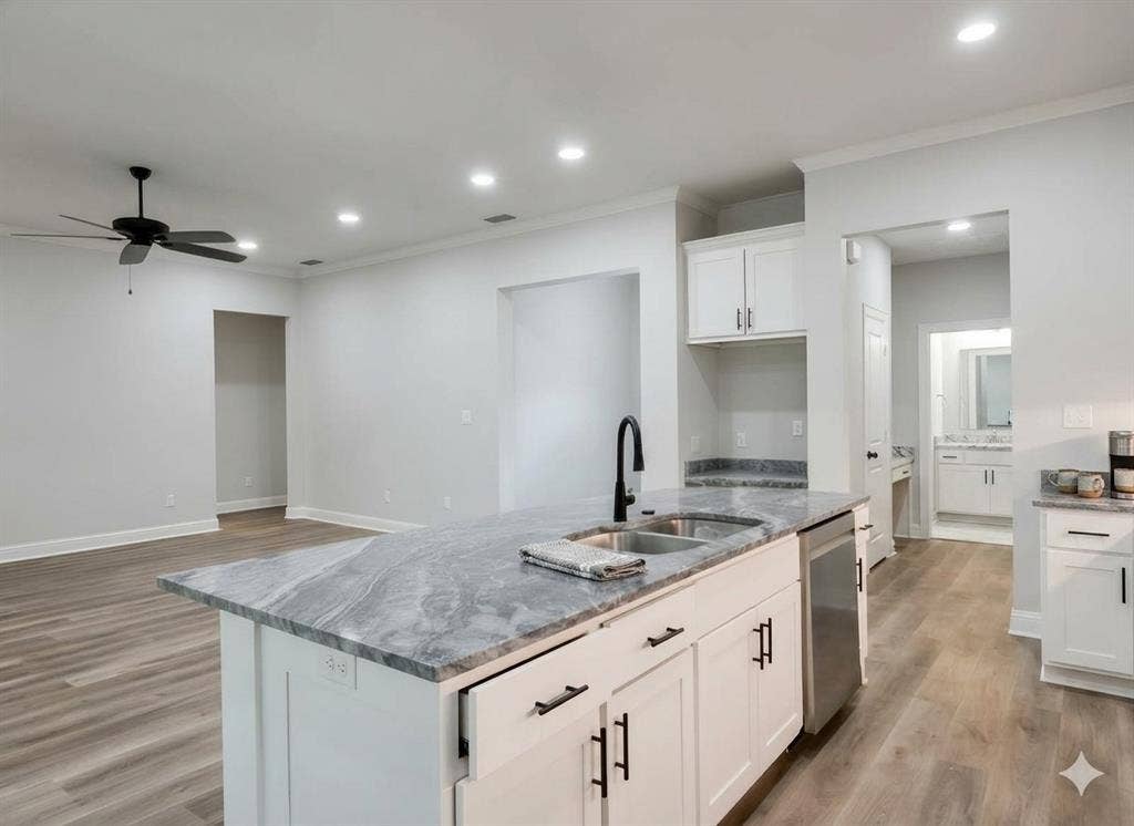 11034 Oak Springs Cove, Tyler, TX 75703 Kitchen island featuring a dual basin sink with a matte black faucet, integrated dishwasher, and stone countertop