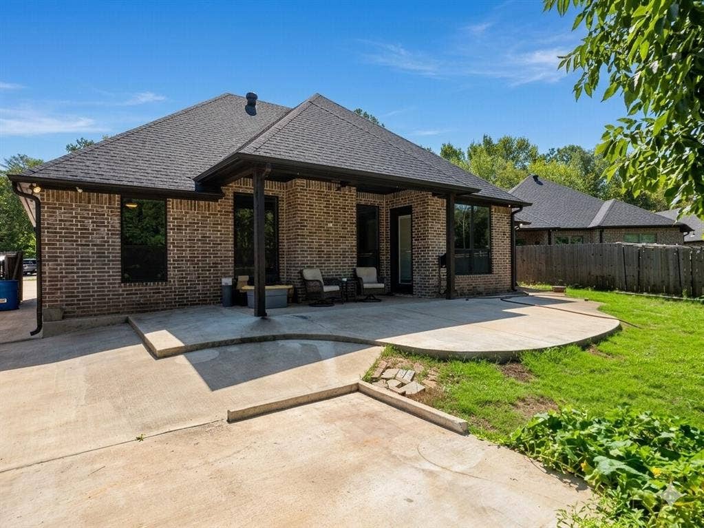 11034 Oak Springs Cove, Tyler, TX 75703 Brick exterior with a covered patio, expansive concrete hardscaping, and a lush lawn