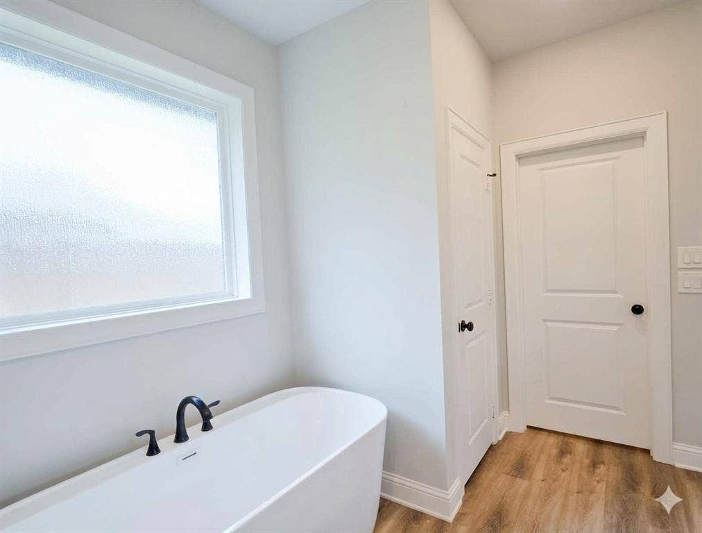 11034 Oak Springs Cove, Tyler, TX 75703 Freestanding soaking tub with matte black fixtures, wood-finish flooring, and a privacy window