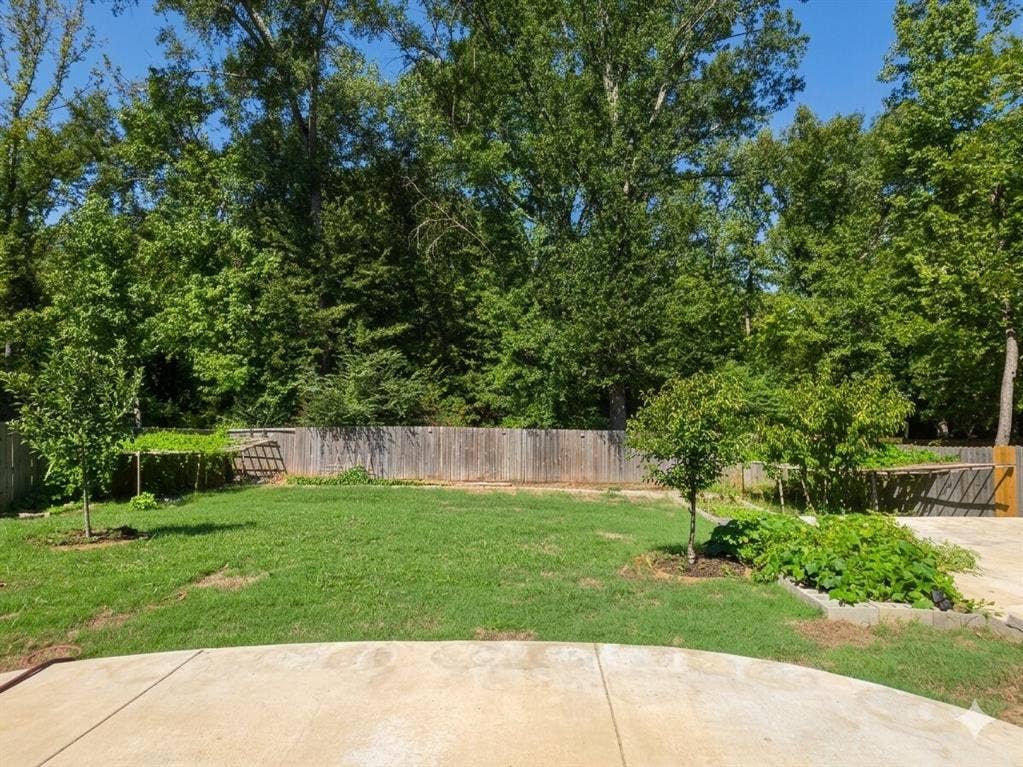 11034 Oak Springs Cove, Tyler, TX 75703 Expansive backyard featuring a concrete patio, a privacy fence, and mature trees