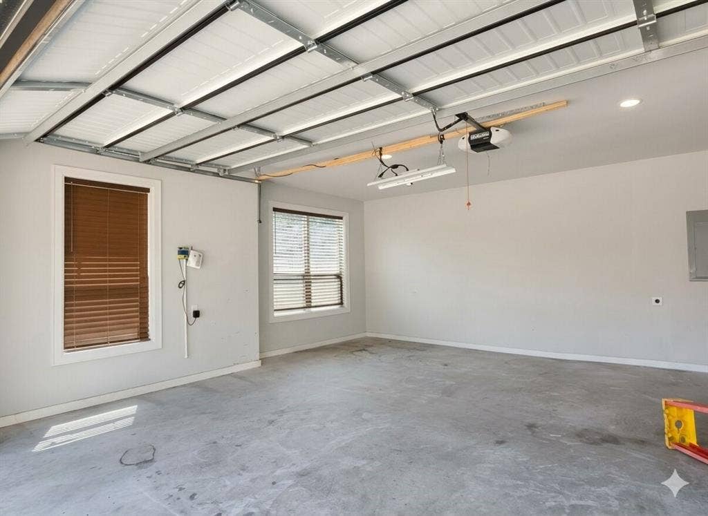 11034 Oak Springs Cove, Tyler, TX 75703 Attached two-car garage featuring a concrete floor, two windows with blinds, and white walls