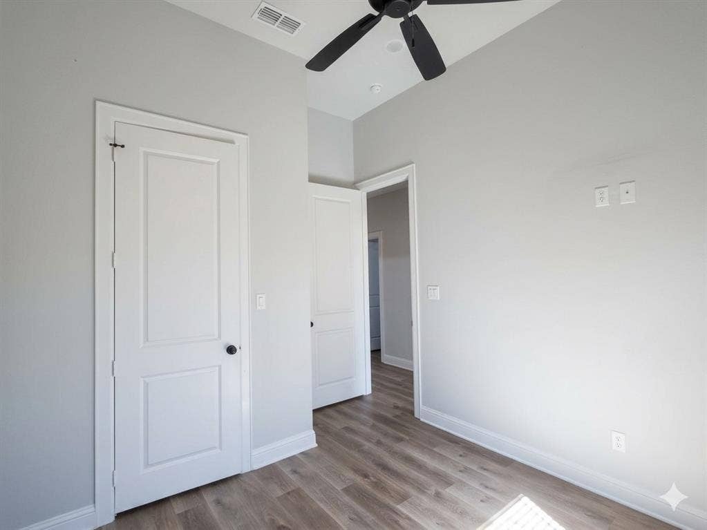 11034 Oak Springs Cove, Tyler, TX 75703 Wood-finish flooring, white panel doors with black hardware, vaulted ceiling, and a ceiling fan