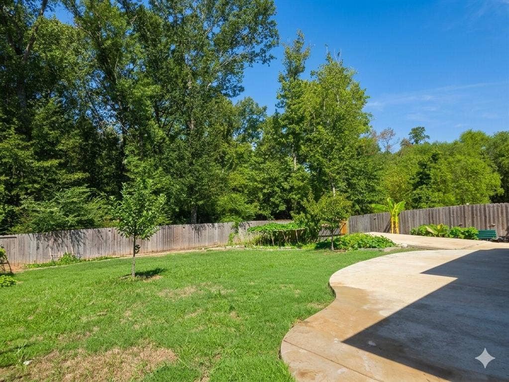 11034 Oak Springs Cove, Tyler, TX 75703 Expansive backyard featuring a curved concrete patio, established lawn, and a perimeter wooden fence