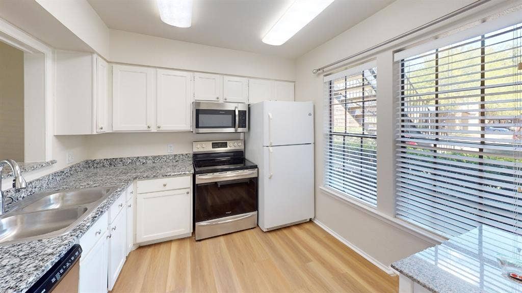 5335 Bent Tree Forest Drive, #150, Dallas, TX 75248 Kitchen featuring white cabinetry, wood-finish flooring, stainless steel appliances, and dual windows
