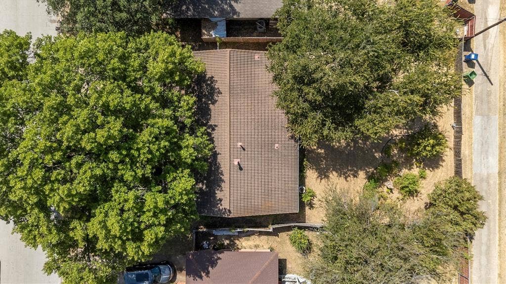 1013 Bandera Lane, Garland, TX 75040 Brown shingle roof with two vents, surrounded by mature trees and a rear yard