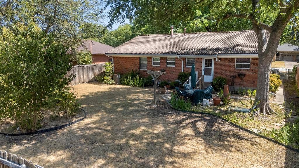 1013 Bandera Lane, Garland, TX 75040 Brick exterior with a tiled roof and a private fenced yard