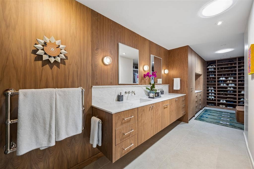 The beautifully renovated primary bath includes a wet room with soaking tub and dual shower heads, custom walnut double vanity with Waterworks plumbing fixtures, and direct access to a custom-designed closet.