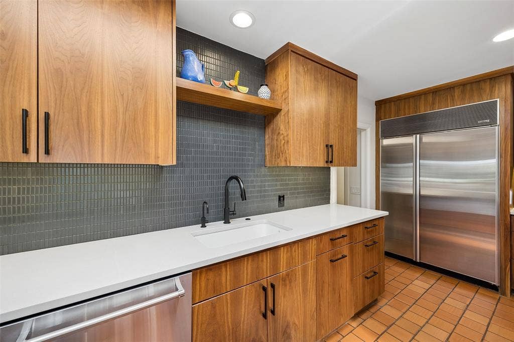 Kitchen features warm rift-cute white oak cabinetry with a Sub-Zero refrigerator, and beautiful backsplash tile.