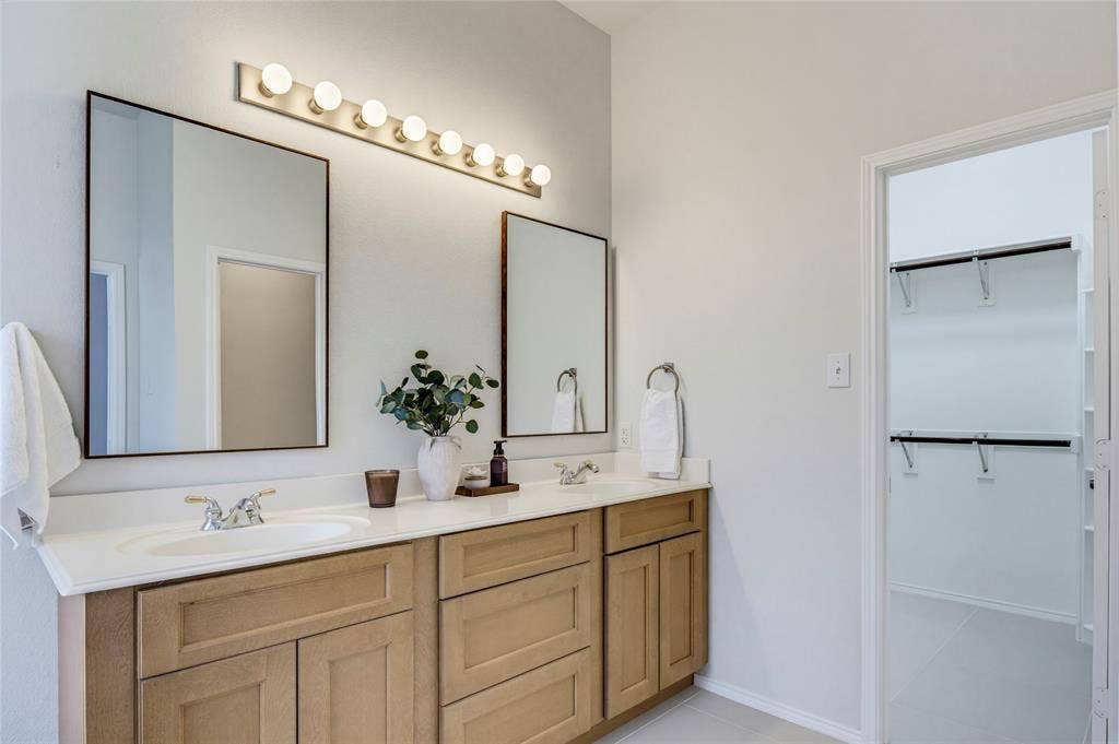 3408 Loblolly Lane, McKinney, TX 75070 Bathroom updates include fresh paint, the wood vanity, mirrors, and beautiful tile floor.