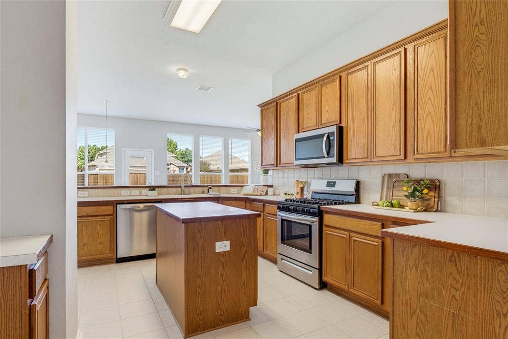 3408 Loblolly Lane, McKinney, TX 75070 The kitchen features stainless steel appliances including a gas range and has plenty of cabinets for storage.