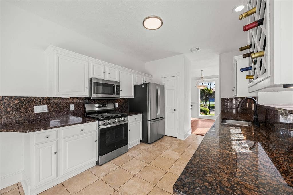 4203 N Capistrano Drive, Dallas, TX 75287 Photograph looking from breakfast area back through kitchen toward dining room. All new GE appliances including microwave, dishwasher, gas stove with electric oven, GE French Door Refrigerator/freezer drawer.