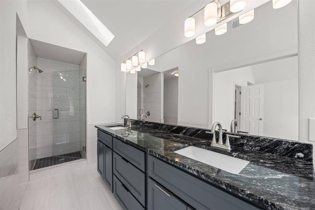 4203 N Capistrano Drive, Dallas, TX 75287 Master Bath showing custom vanity, soft closing drawers and doors, granite countertop, new rectangular undermount sinks, new brushed nickel faucets, mirror and lighting. The new shower enclosure includes brushed nickel controls and a frameless glass shower door.