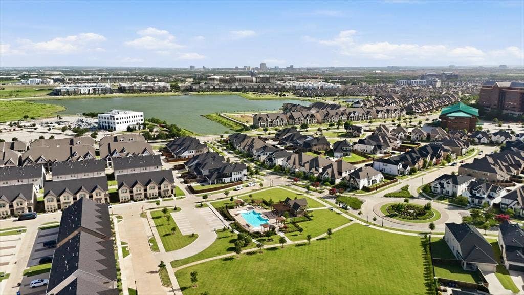 12952 Wymeth Drive, Farmers Branch, TX 75234 Aerial perspective showcasing the community with a large lake and multiple swimming pools, playgrounds and