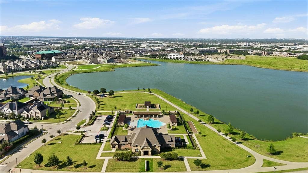 12952 Wymeth Drive, Farmers Branch, TX 75234 Aerial perspective showcasing the expansive community with a large lake and multiple swimming pools, playgrounds and