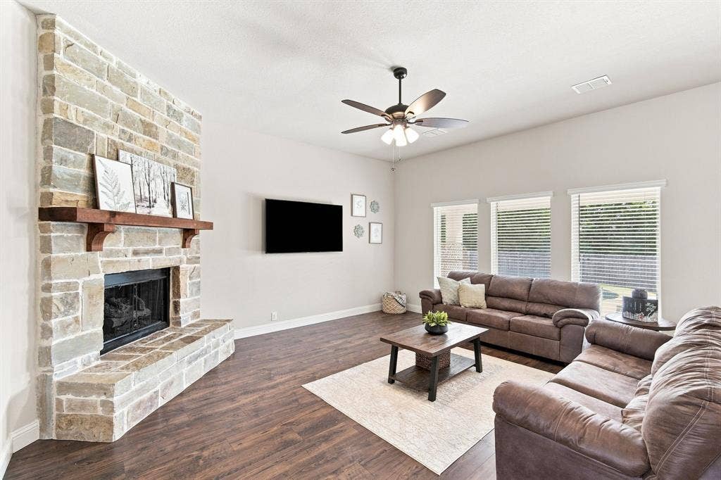 Your grand living area features rich wood flooring, large windows, and a stunning stone-to-ceiling fireplace